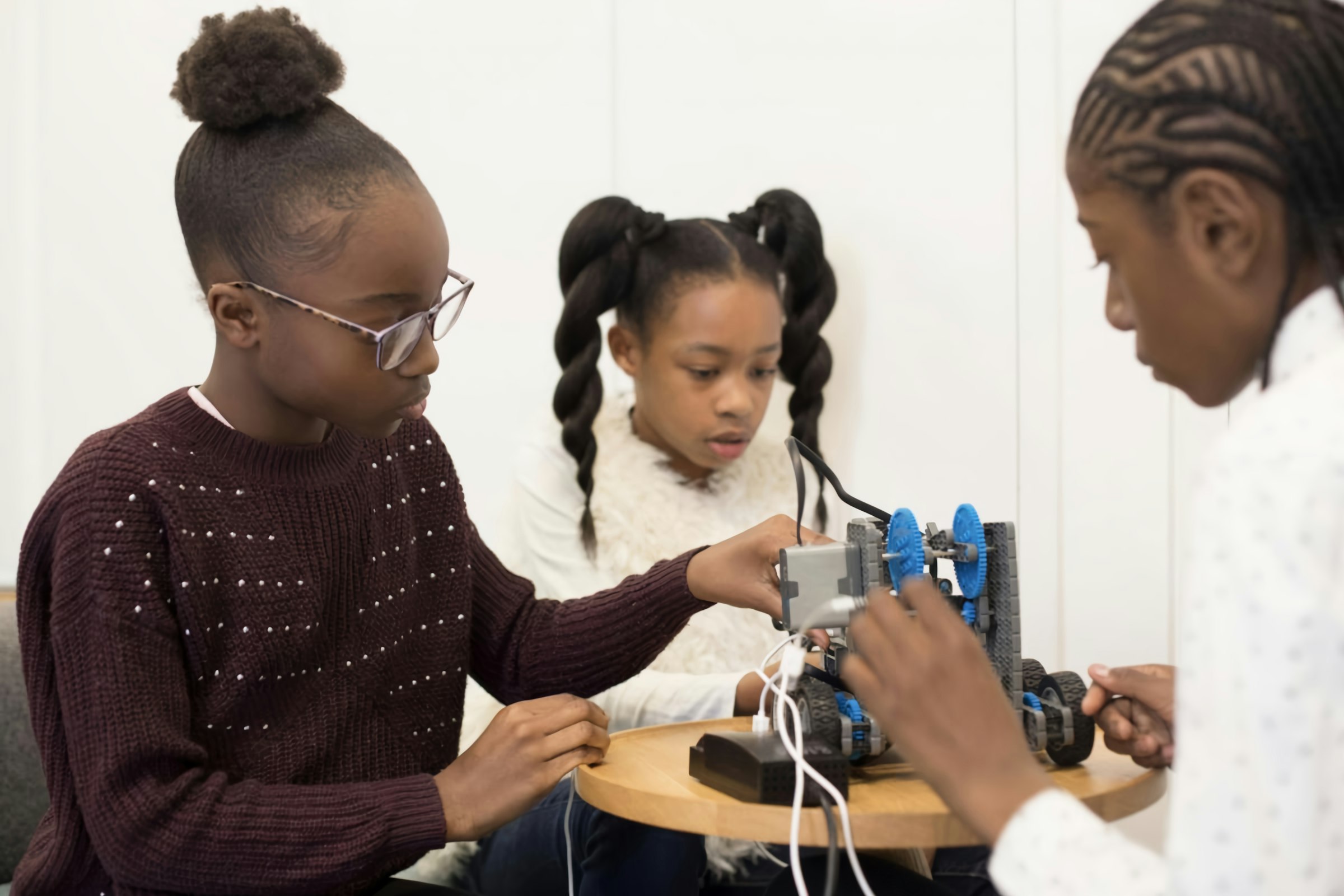 Three girls wiring and building a small robot together
